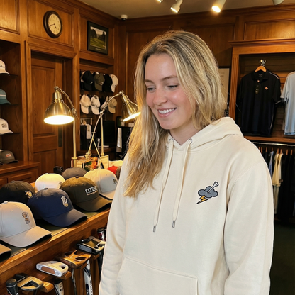 Woman wearing a cream hoodie with a logo in a store setting