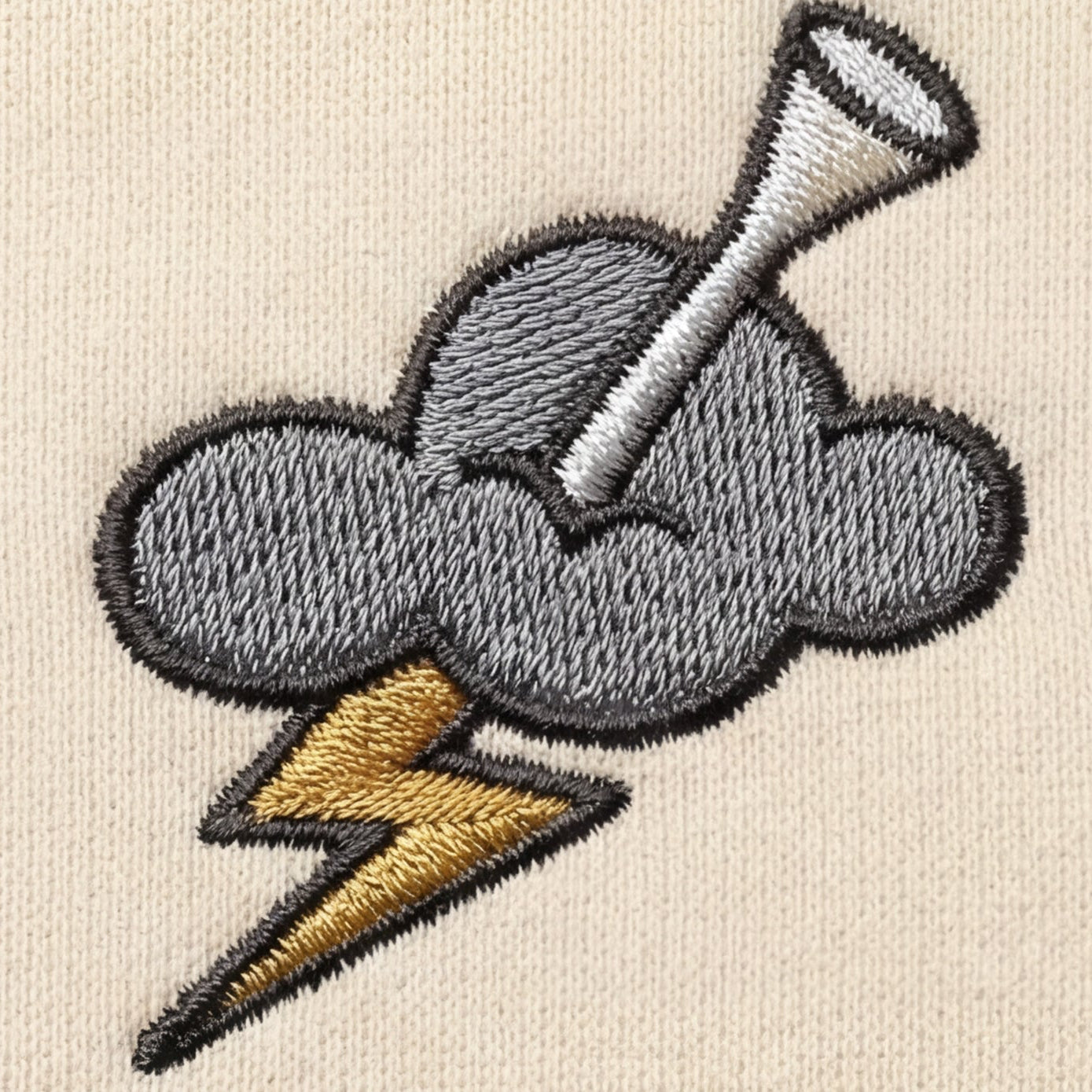 Embroidered design of a cloud with a lightning bolt and a golf tee on a beige background