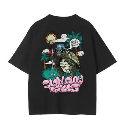 A white crew neck t-shirt with a graphic print of a turtle in a sun hat and sunglasses, playing a game of golf, and the text 'SLOW PLAY KILLS' below it.