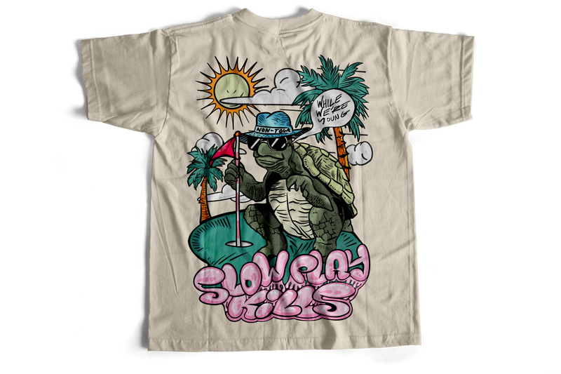 Beige t-shirt with a graphic of a turtle wearing sunglasses and a hat, with palm trees and text on a white background.